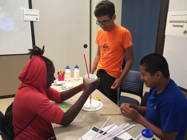 Students engaged in a collaborative STEM activity, experimenting with materials to explore concepts of mathematical thinking.