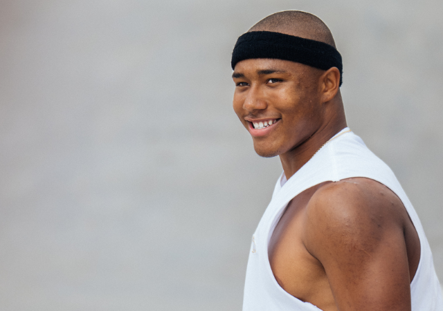 Cordano Russell smiles wears a black sweatband and white tank. Russell will compete in Men’s Street Skateboarding for Team Canada during the 2024 Summer Olympic Games in Paris.
